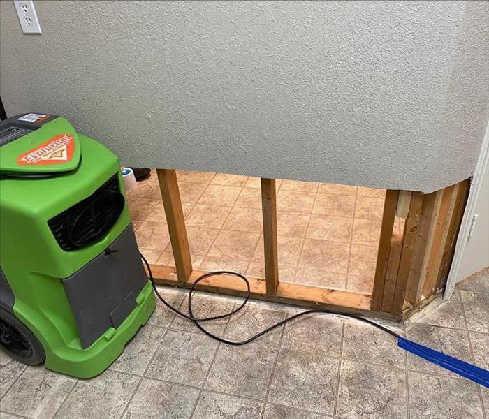 Flood cuts in a wall next to a green air mover. 