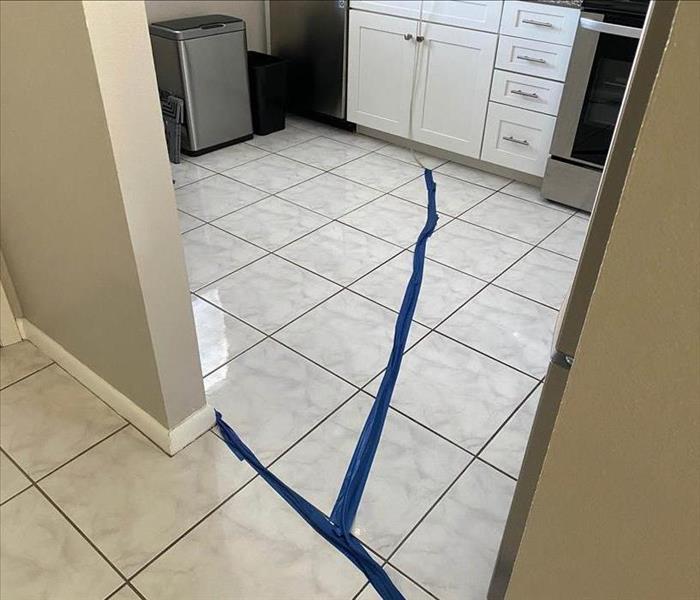 Room with white tile and blue tape on the floor. 