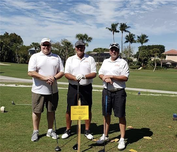 Three men standing with golf clubs. 
