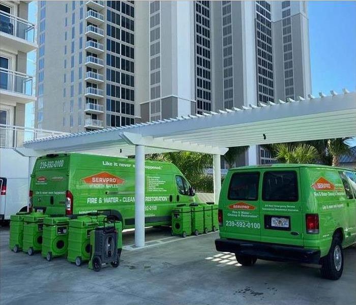 Two green vans parked outside a building, air scrubbers placed beside vans