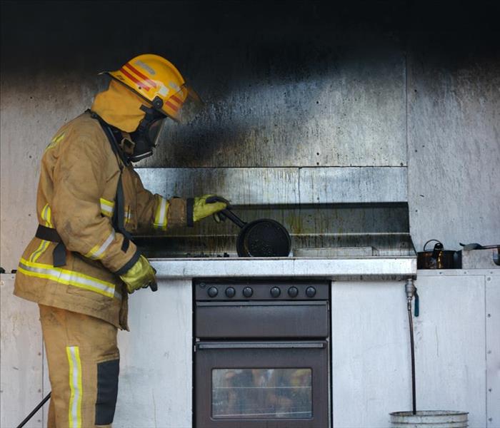 The aftermath of a kitchen oil fire. A firefighter investigating the cause.