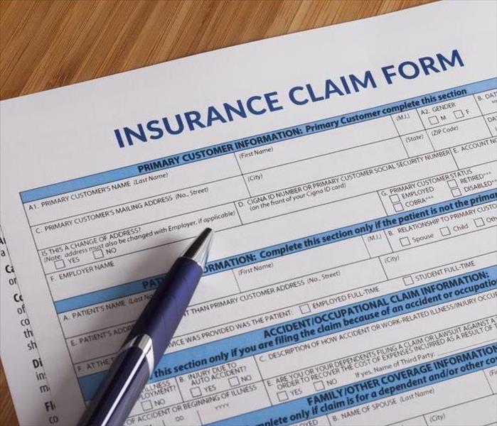insurance claim form and a blue pen